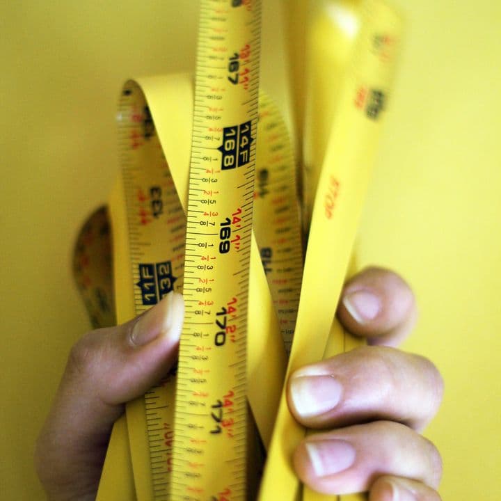 A left hand holding an extended tape measure which has been folded